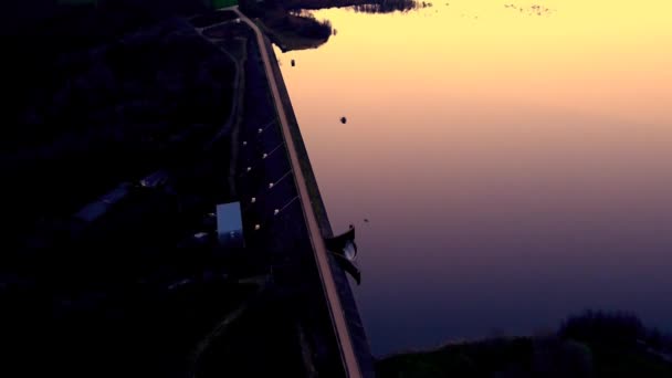 オレンジ色の日の出光が水面に反射するプレサビレッジでの夜明け滑らかな穏やかな湖の上に空中 — ストック動画