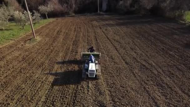 白いクローラトラクターと緑のシーダーでフィールドを播種する空中ショット — ストック動画