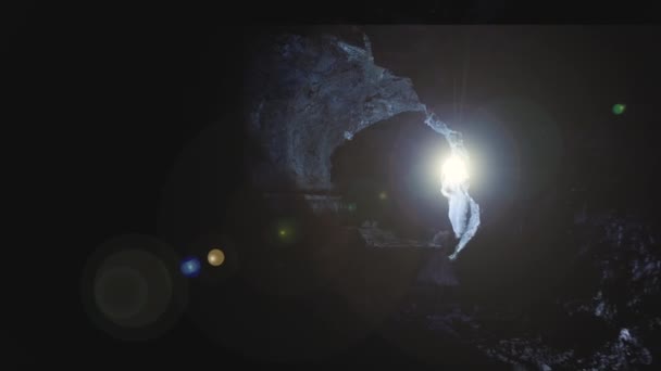 宇宙飛行士の空中からの眺め頭に明るい光を持つ暗い洞窟を探索する — ストック動画