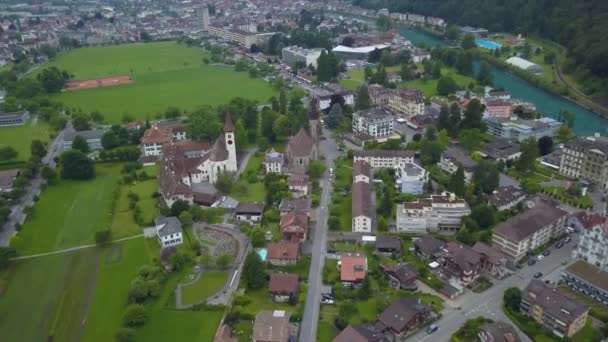 瑞士阿尔卑斯山畔因特拉肯山谷的天主教和新教教堂被布满树木的山丘环绕 空中俯瞰 — 图库视频影像