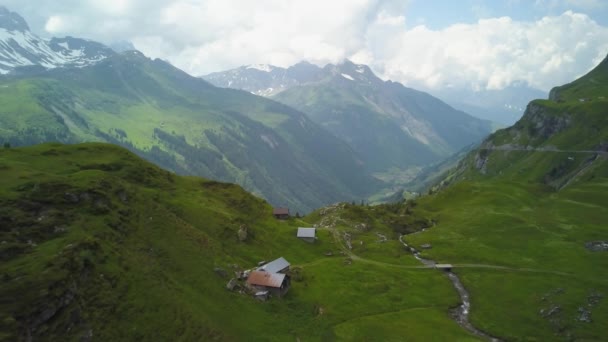 緑の谷の丘の中腹にある小さなコテージ 曇りの日に背景にある緑豊かな山々や森 スイスアルプスを飛んで空中ドリー — ストック動画