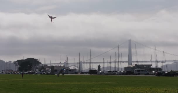 旧金山的一个刮风的日子里 孩子们在放风筝 背后是海湾大桥 — 图库视频影像
