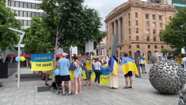 世界中からの支持者は 民主主義の重要性の認識を高め ロシアによる違法な侵略を拒否するための旗 サイン プラカードを設定するブリスベン広場で一緒に結集しました — ストック動画