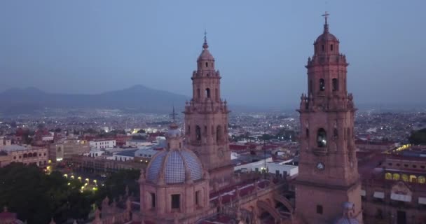 黎明时分 无人机飞越墨西哥莫雷利亚上空 无人机从大教堂向后飞去 揭示了身后的城市和山脉 — 图库视频影像
