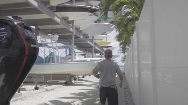 Man Walks Alongside Large Boat Rack Bright Sunny Day — Stock video