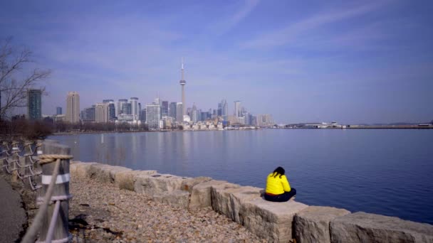 Person Toronto Trillium Park Headphones Sitting Lake Bright Yellow Jacket — стоковое видео