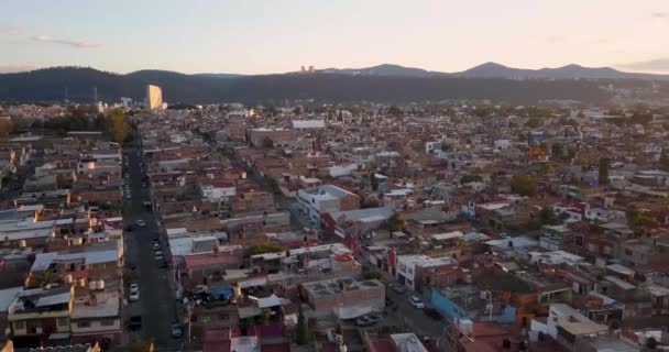 ドローンは日没時にメキシコのモレリア上空を飛ぶ 街を明らかにするためにズームアウトエリアの上にすぐに後方に飛ぶドローン — ストック動画