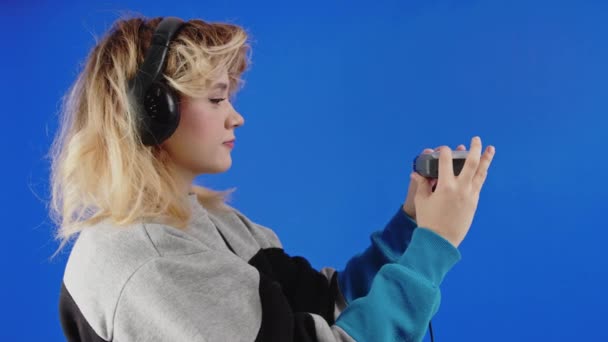 10代の白人の少女がカセット オーディオ プレーヤーを閉じて 音楽を聴くために再生を押す 青い画面の背景 — ストック動画