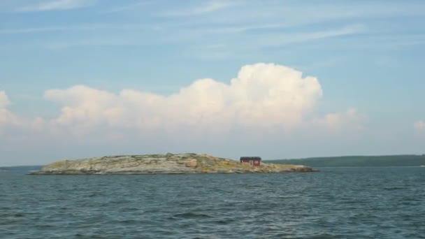 阳光灿烂的日子里 大海中央一个岩石小岛上的一座孤立的小红屋 — 图库视频影像