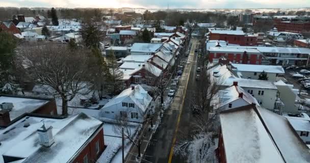 美国的一个小镇被冬天的雪覆盖着 日落时 屋顶上的景色映照在道路的上方 安静的空中设置射击 — 图库视频影像
