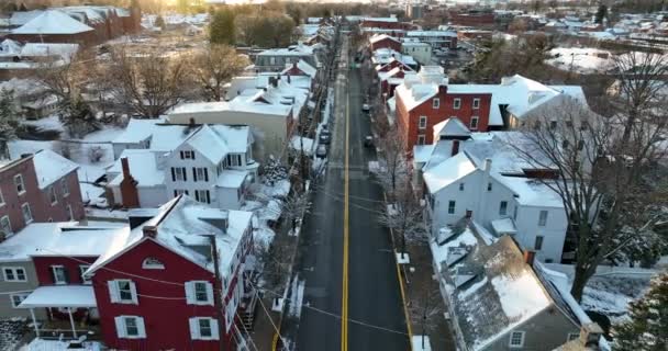 Amazing winter snow scene in small town USA. Pullback reveal of Christmas holiday scene with homes and church steeple in sunset light. Cinematic reveal shot.