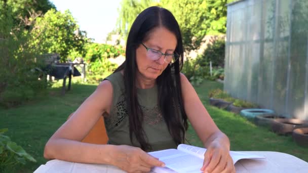 Evinin Arka Bahçesinde Kitap Okuyan Orta Yaşlı Bir Kadın — Stok video