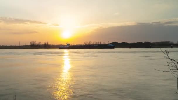 シュレルト川の産業用ボートの後ろに沈む黄金の太陽 タイムラプスビュー — ストック動画