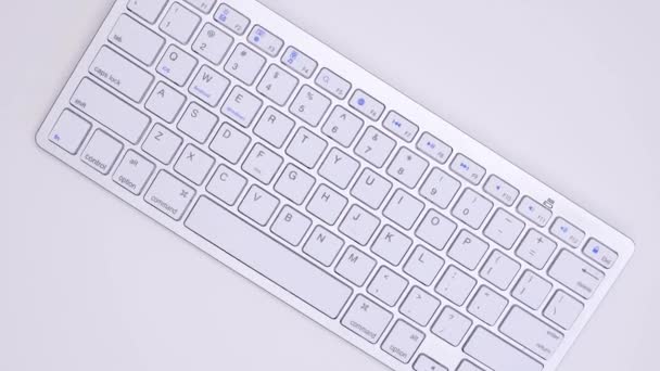 文字とスペースバーとファンクションキーで回転し 上から下に見られる白い金属製の小さなキーボード — ストック動画
