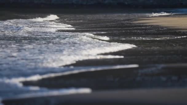 波はエルスフィヨルドの砂浜の浅瀬でゆっくりと転がります 白い泡が立ち上がり 砂に飲み込まれて消えます スローモーション パン右 — ストック動画