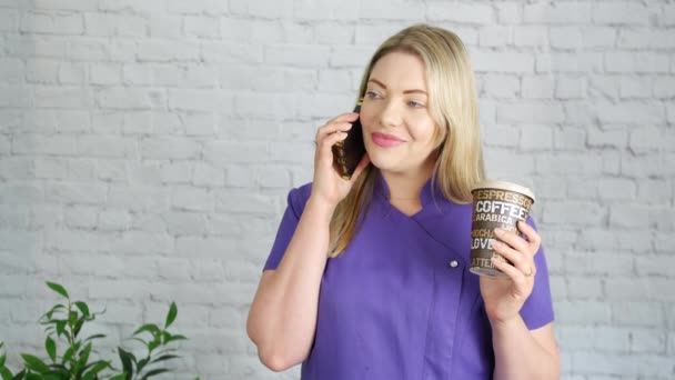 Szczęśliwa Blondynka Trzymająca Kawę Kosmetyczka Rozmawia Przez Telefon Przerwie Salonie — Wideo stockowe