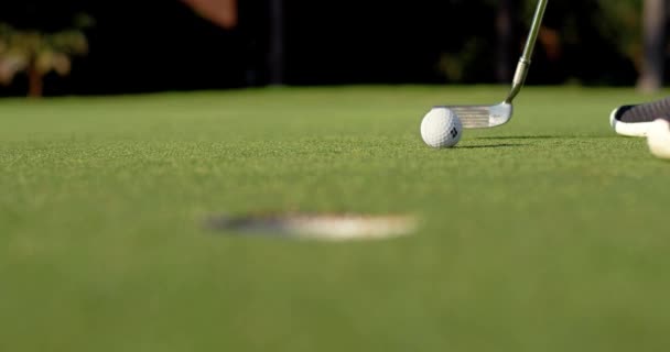 A golf ball slowly rolls toward a hole on a putting green before it goes in. Shot in slow motion in 4k at 120fps.