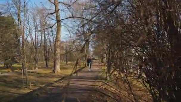 一个穿着雅致衣服的男人 骑着电动车在一个城市公园的早晨的氛围中穿行 — 图库视频影像