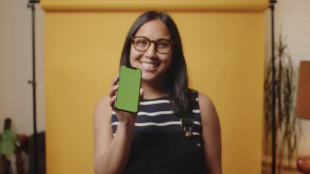 若い幸せなアジアの女性は 緑の画面を表示するカメラに向かって彼女の携帯電話をプッシュ — ストック動画