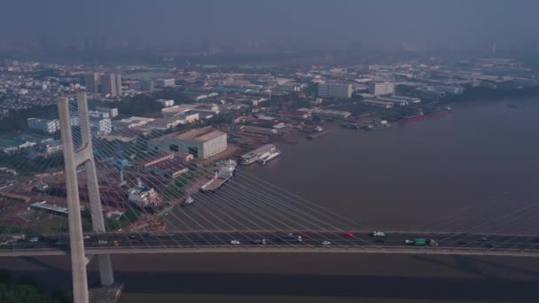 在越南胡志明市Saigon河对岸的Phu My桥的缓慢跟踪使得无人驾驶飞机在早晨的浓雾中拍摄到港口 车辆驶过桥 — 图库视频影像