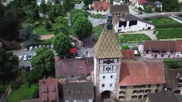 A rearward aerial drone footage of the clock tower while revealing the houses, the roads, and the whole village. This is located at the fortified village of Bergheim, Haut-Rhin. This looks cinematic.