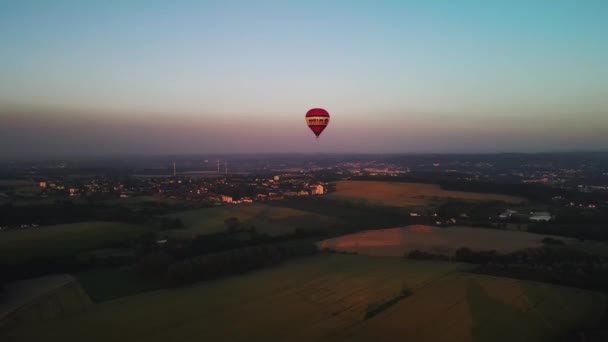 Colorful hot air balloon flying above Bochum Wattenscheid, Germany over the foggy sky at dawn with a beautiful sky background. Zoom in shot with high altitude aerial drone wide view 4K UHD