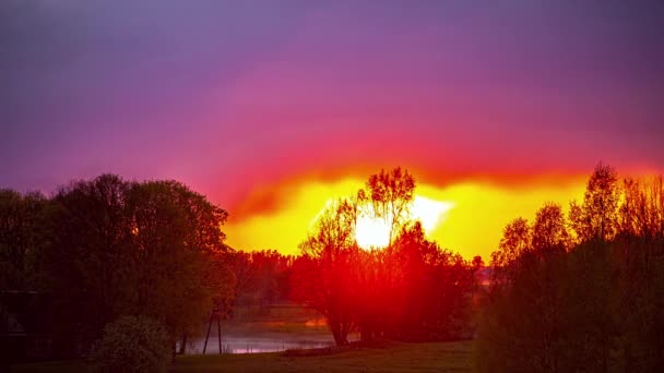 湖の上に沈む夕日の息をのむようなショット 日没時には強い雲が太陽に照らされる タイムラプス動画 — ストック動画