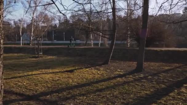 Menino Cavalga Através Parque Ensolarado Cidade Uma Scooter Elétrica — Vídeo de Stock