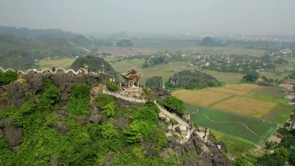 无人机在轨道上向山顶上的旅游景点移动 周围是高山 四周都是稻田 — 图库视频影像