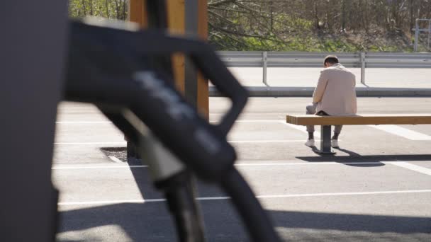 Man Väntar Och Sitter Bänken Vid Laddningsstationen Solen Bred — Stockvideo