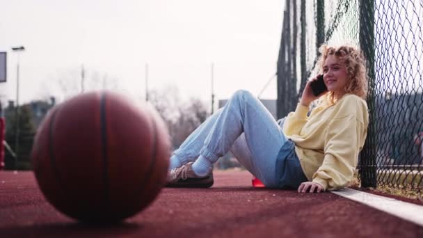 Nastoletnia Blondynka Siedząca Boisku Koszykówki Dzwoniąca Przyjaciółki Zwolnij Trochę Zwyczajny — Wideo stockowe