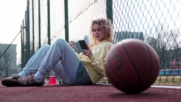 Adolescente Chica Rubia Ropa Casual Sentado Cancha Baloncesto Utilizando Teléfono — Vídeos de Stock