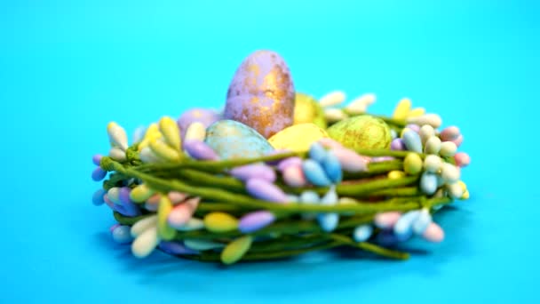 Ручний Знімок Барвистих Великодніх Яєць Зберігаються Квітковому Гнізді Синьому Фоні — стокове відео