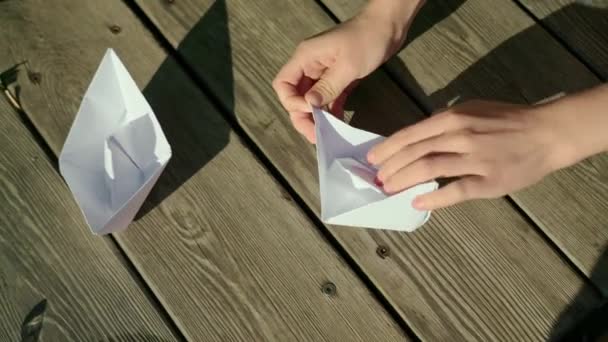 Мальчик Складывает Бумажный Корабль Мальчик Сидящий Деревянной Вешалке Складывает Оригами — стоковое видео