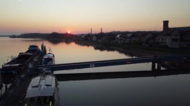 Altın gün batımında Scheldt nehrinin yanında iskelesi olan küçük bir sahil kasabası, havadan yükselme manzarası