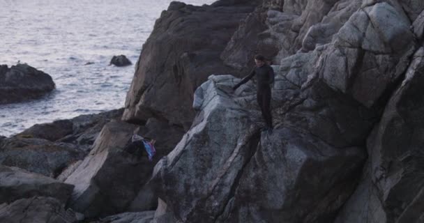 成年雄性爬上悬崖 日落时跳入大海 — 图库视频影像
