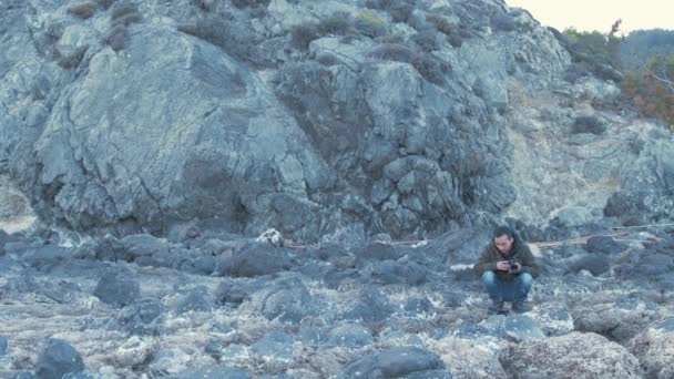 Młody Człowiek Spacerujący Kamienną Linią Brzegową Kamerą — Wideo stockowe