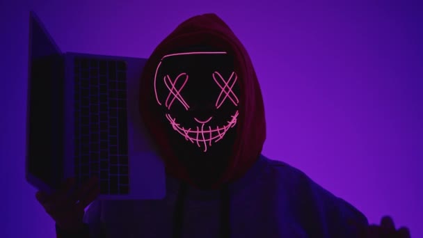 Анонимный Хакер Держит Ноутбук Темной Комнате Неоновыми Огнями — стоковое видео