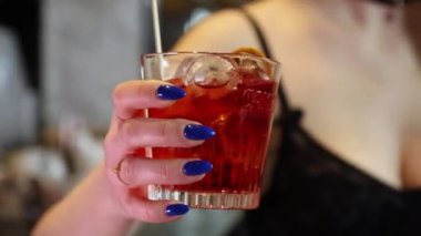 detail of model's hand with blue nails holding a cocktail