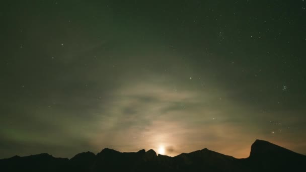 A timelapse of the night sky. Stars and northern lights shine through the clouds.