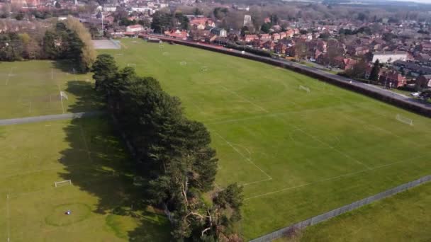Top rotating aerial view on lush green football field hidden in forest. Public city park with sport amenities and recreation zone for athletes. Bright green stand out soccer field