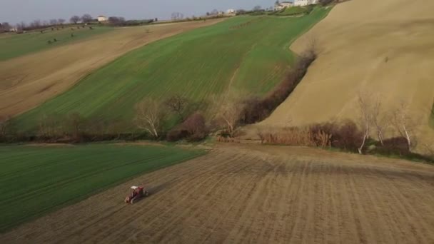 在风景秀丽的山地农场 用红色拖拉机耕田的空中农业耕作 无人驾驶飞机在身后的尘土飞扬 为种植新作物准备了土壤 — 图库视频影像