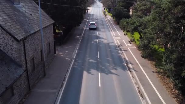 緑のフィールドの間の台地上に空のアスファルトの道路 空中ビュー 山の範囲の間に捨てられたフィールドを横断する長いオープン道路上のフライト 風光明媚なハイランドの方法です 車でのロードトリップの概念 — ストック動画