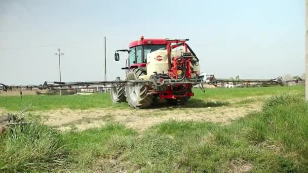 灌漑や農薬散布のための取り付けられた噴霧器と赤の近代的なトラクター 緑の牧草地の農地での季節の仕事 — ストック動画