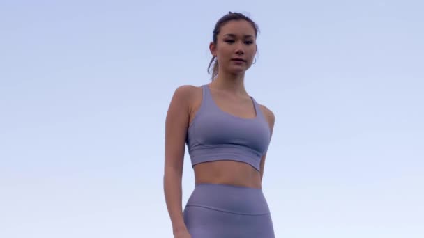 美丽的亚洲女人在摆姿势时调整运动服 慢速低角度 — 图库视频影像