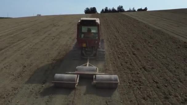 Drone Follow Red Tractor Rolling Soil Creating Better Seedbed Germinating — Vídeo de Stock