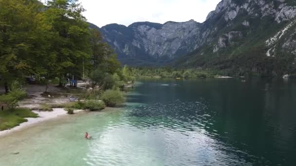 位于斯洛文尼亚Gorenjska的Bohinj湖 在海滨放松和在清澈翡翠湖中游泳的游客空中无人机视图 — 图库视频影像