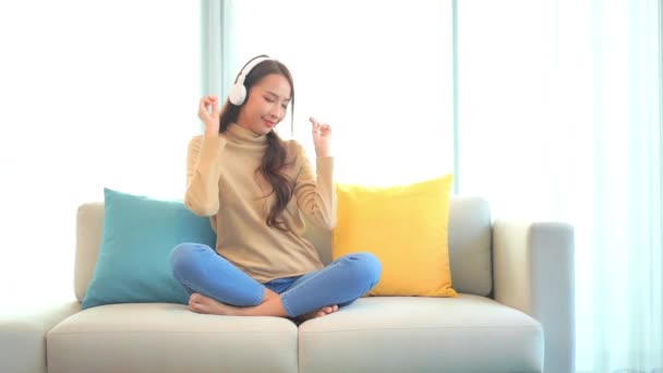 Μια Νεαρή Γυναίκα Κάθεται Στον Καναπέ Λικνίζεται Στη Μουσική Ενώ — Αρχείο Βίντεο