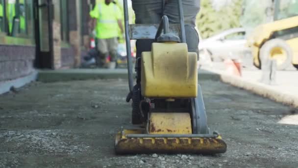 コンパクトな歩道砂利にプレートコンパクタを使用して建設労働者 都市公務員 — ストック動画