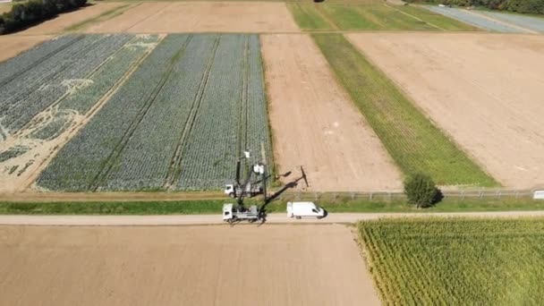 Zdjęcie Lotnicze Dwóch Elektryków Dźwigach Naprawiających Linię Energetyczną Nad Polami — Wideo stockowe